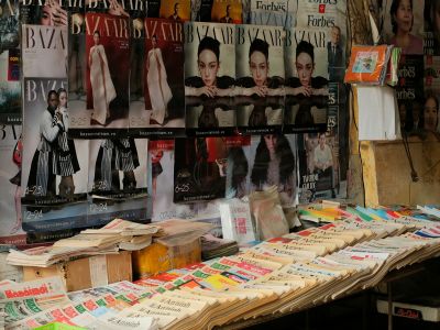 Magazines and newspapers laid out side by side on an outdoor news stall.