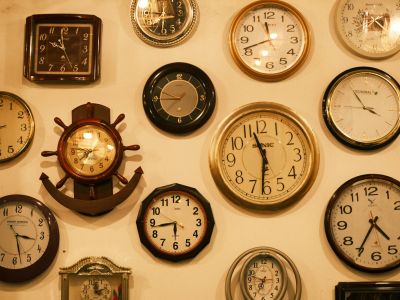 A wall crowded with dozens of different clocks, each showing a different time.
